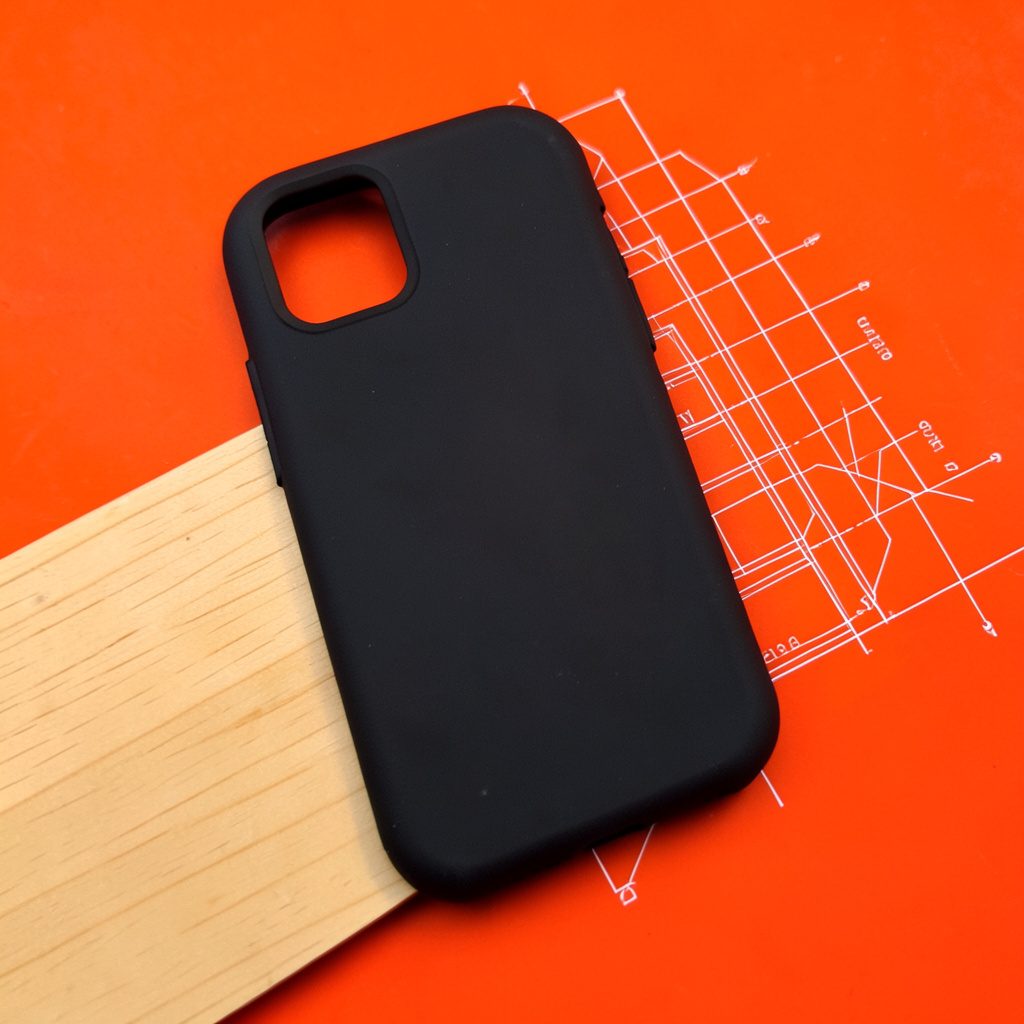 Slim protective phone case in solid matte black with precise cutouts, resting diagonally on a light wooden surface